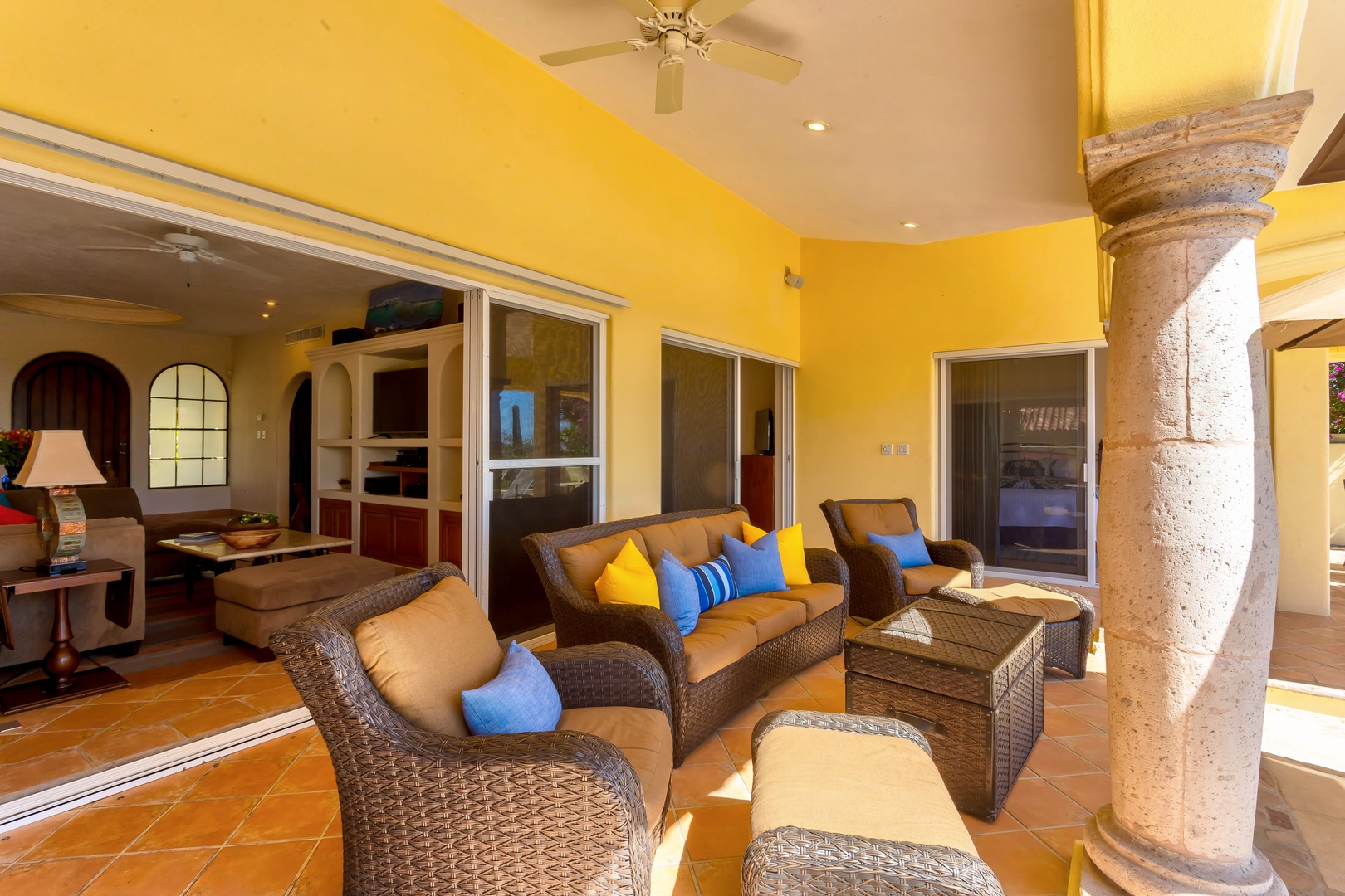 Unwind in your private covered terrace with plush wicker seating and vibrant yellow walls creating a cheerful, tropical retreat.