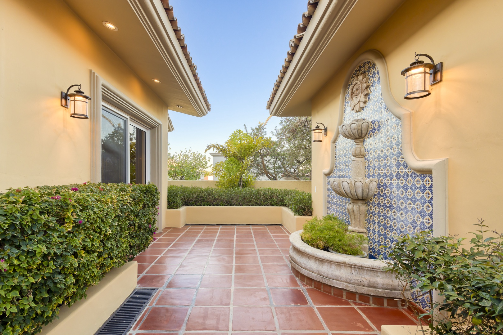 Elegant Spanish-style courtyard entrance features decorative tile fountain and terracotta flooring creating a welcoming arrival experience.