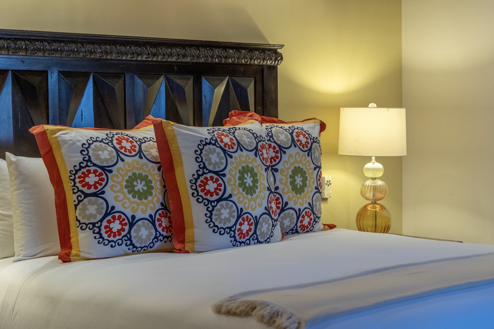 Sink into crisp linens and plush pillows on your elegantly carved bed, with colorful accents that brighten your restful retreat.