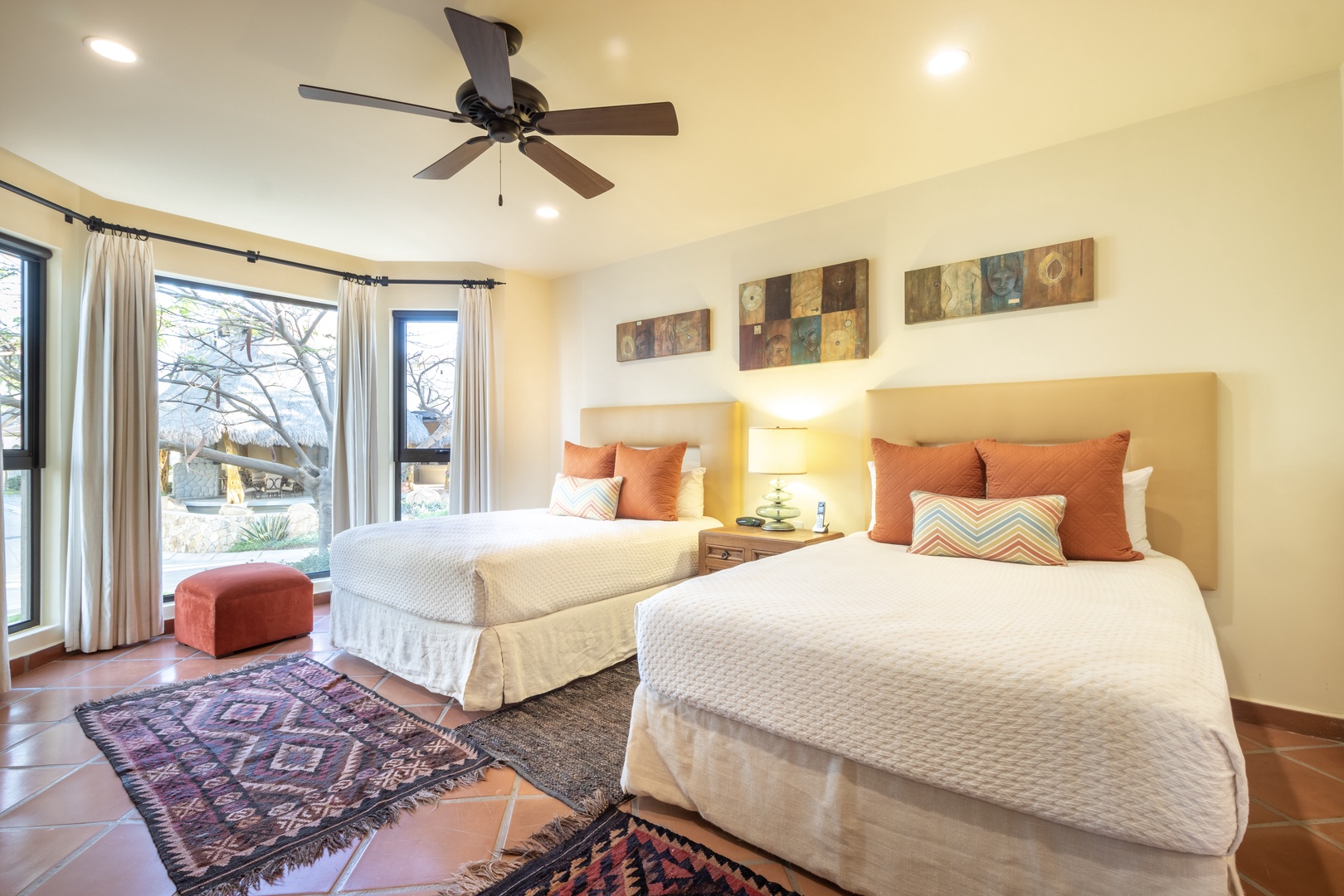 Relax in your spacious bedroom with two plush beds, natural light, and a warm Southwestern aesthetic. A ceiling fan keeps you comfortable while colorful rugs and artwork create a welcoming retreat.