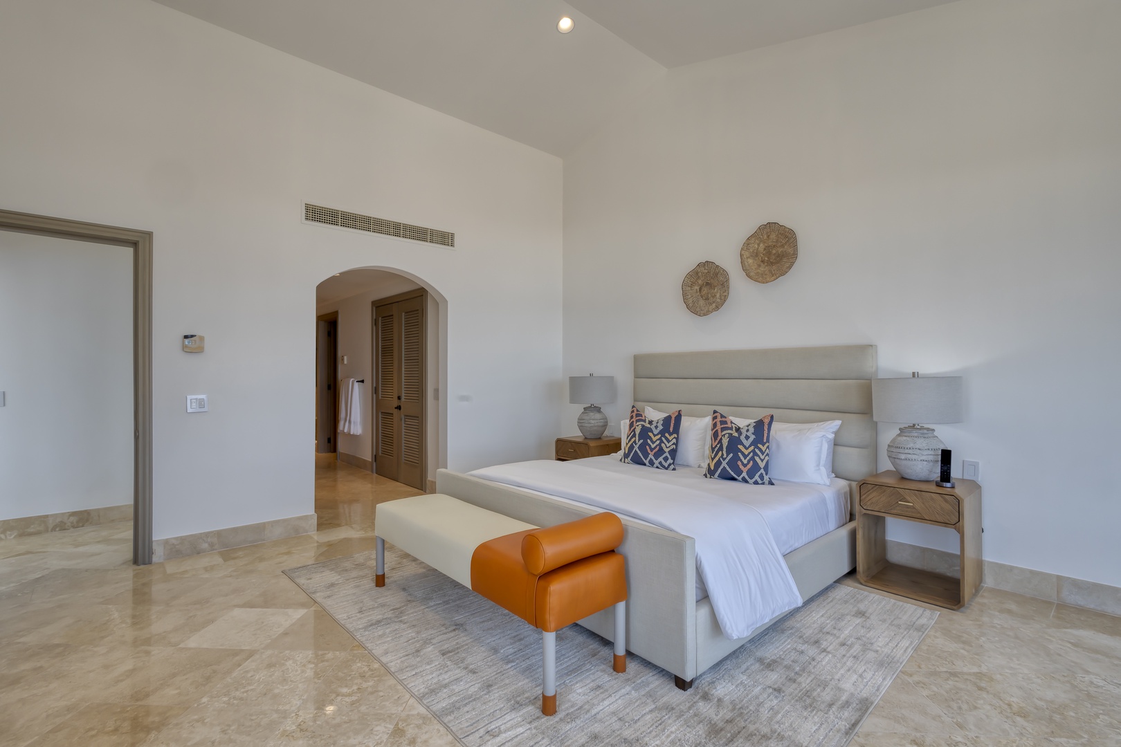Sink into crisp white linens and let the high ceilings and soft natural light create your perfect retreat. Notice the thoughtful touches: decorative wall art, pops of orange, and a climate-controlled haven for your ultimate comfort.