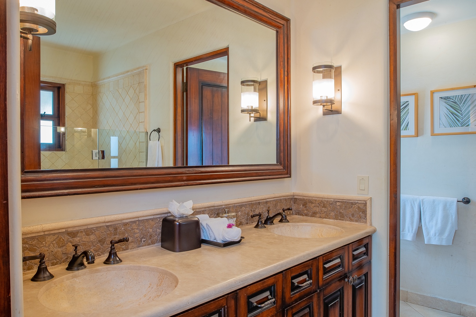 Refresh in your elegant dual-vanity bathroom with marble counters, rich wood cabinetry, and luxury fixtures.