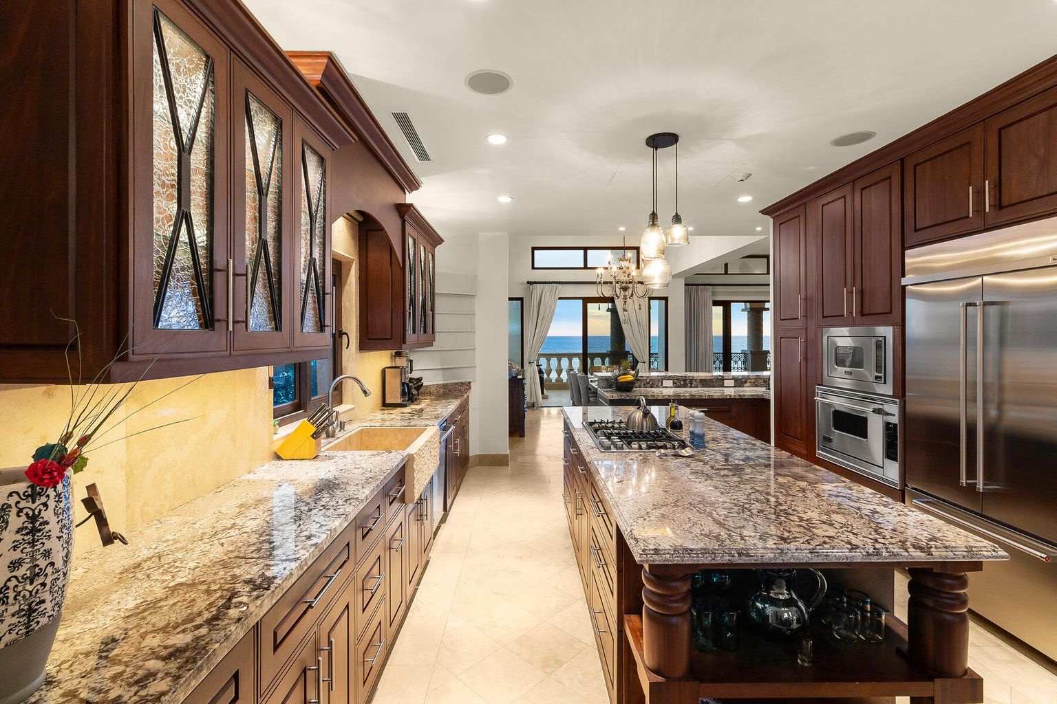 This elegant gourmet kitchen invites you to prepare memorable meals with professional-grade appliances, granite countertops, and a spacious island—all while enjoying glimpses of the ocean beyond.