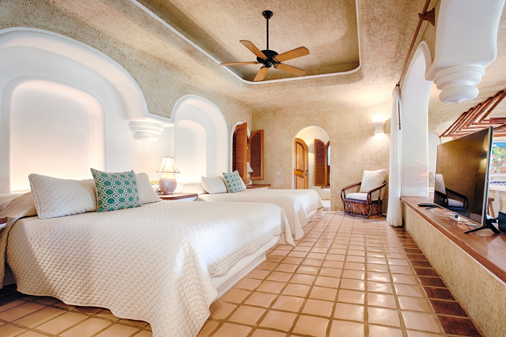 Sink into plush beds with crisp linens under elegant arched ceilings, where warm tile floors and gentle ceiling fan breezes create your perfect retreat.