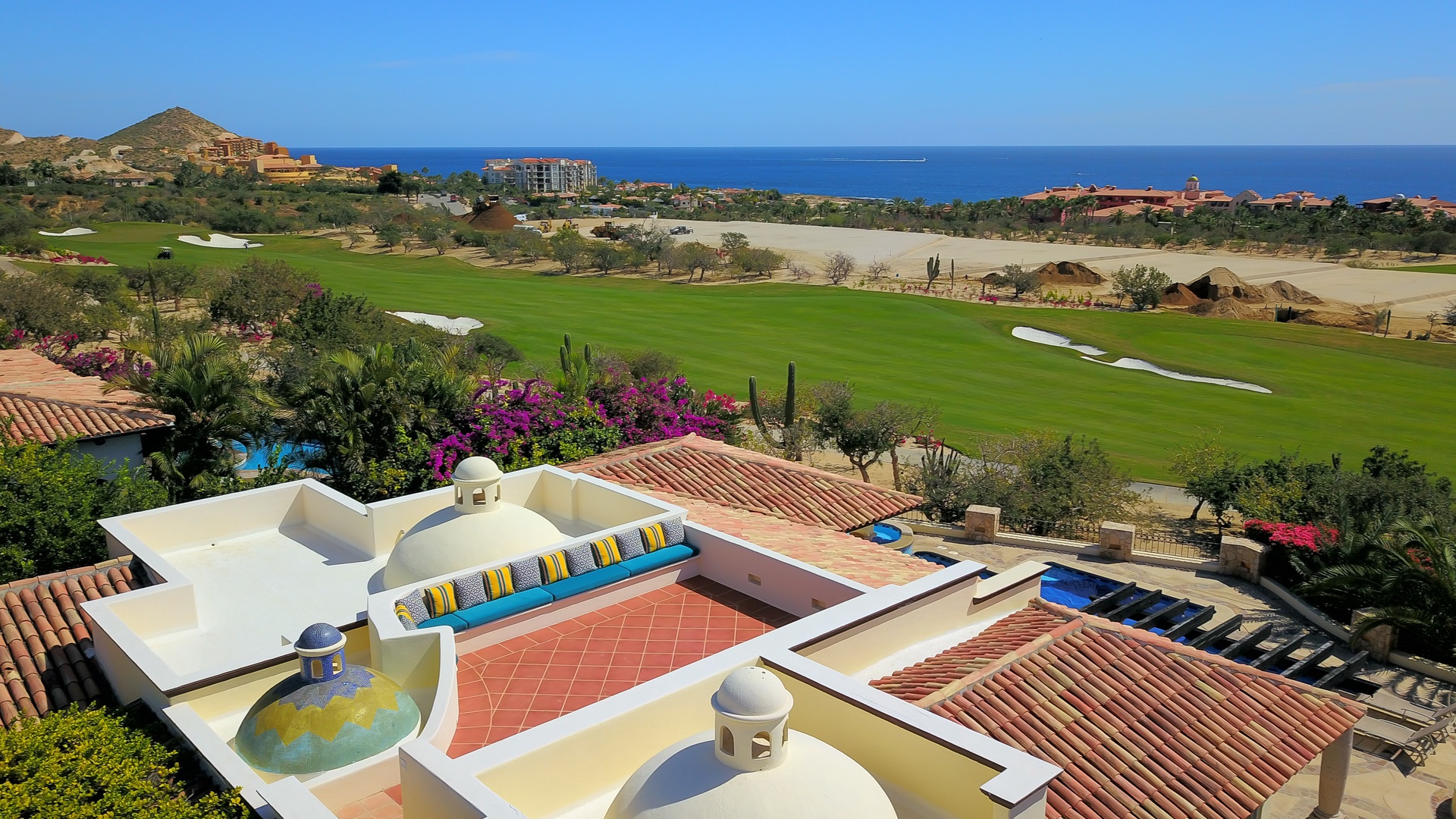 Stunning aerial view of luxury villa with pool overlooking championship golf course and ocean beyond.