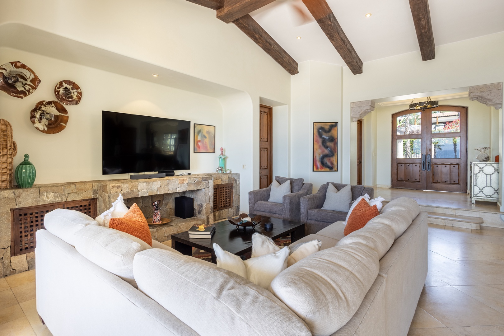 Sink into plush sofas beneath rustic beams, where your stone fireplace awaits cozy evenings and entertainment flows effortlessly.