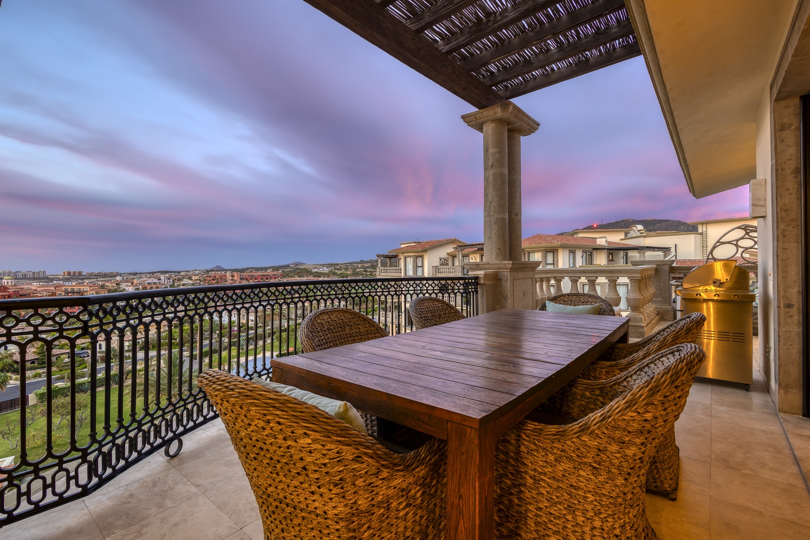 Imagine sipping your morning coffee at this inviting outdoor table as the sky blooms with soft pastels, overlooking stunning rooftops and rolling hills in the distance.