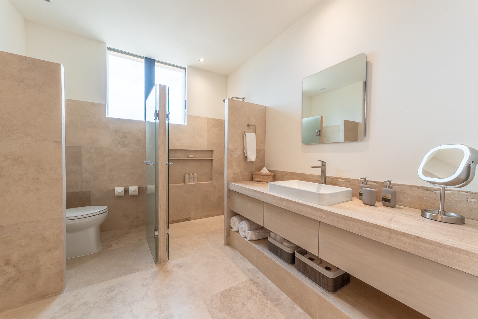 Enjoy your private spa-like bathroom with soft natural light, sleek stone finishes, and a spacious walk-in shower designed for your ultimate relaxation and comfort.