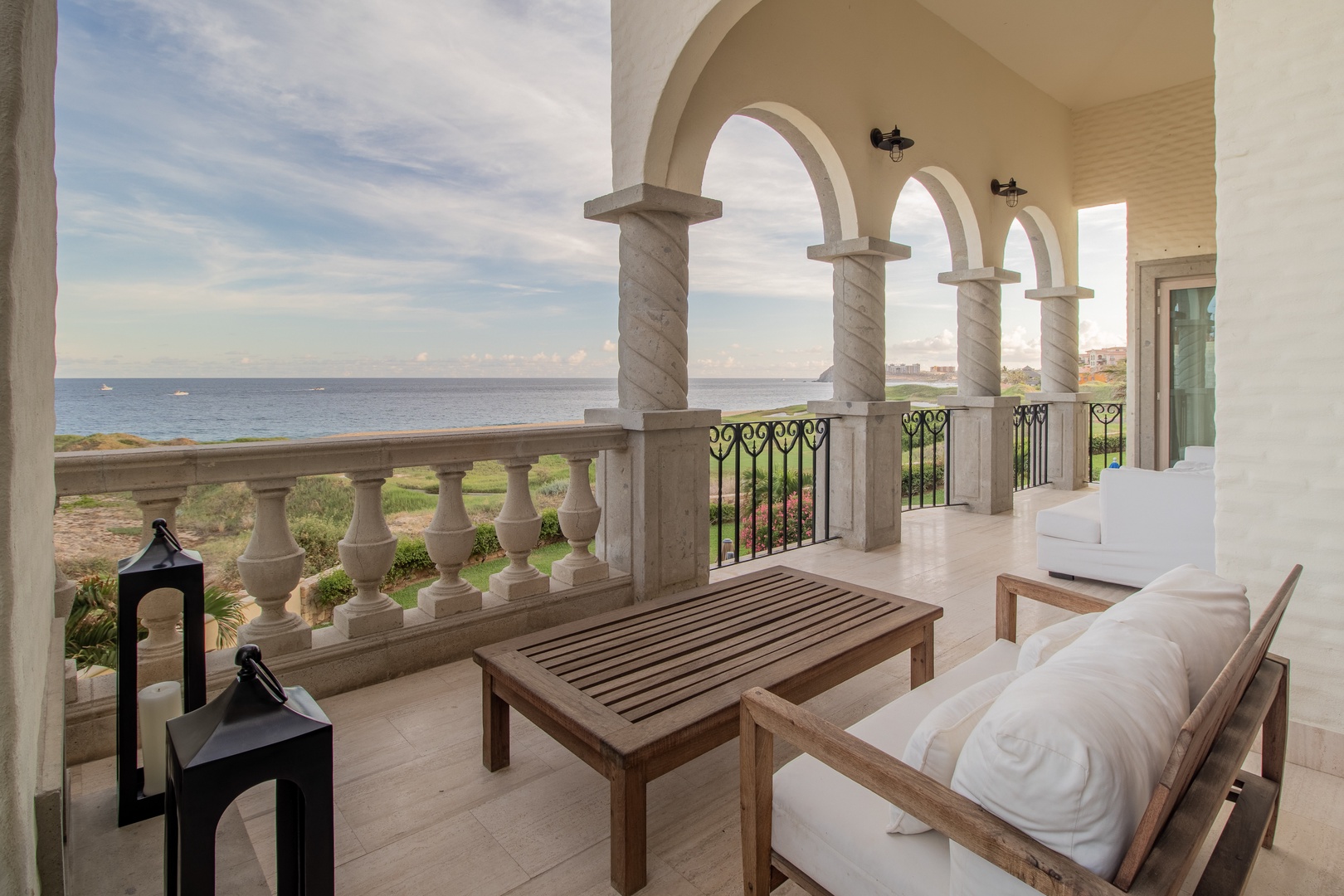 Relax on your private terrace with elegant archways framing stunning ocean views. Unwind on plush seating surrounded by Mediterranean-inspired architecture, your perfect coastal escape.