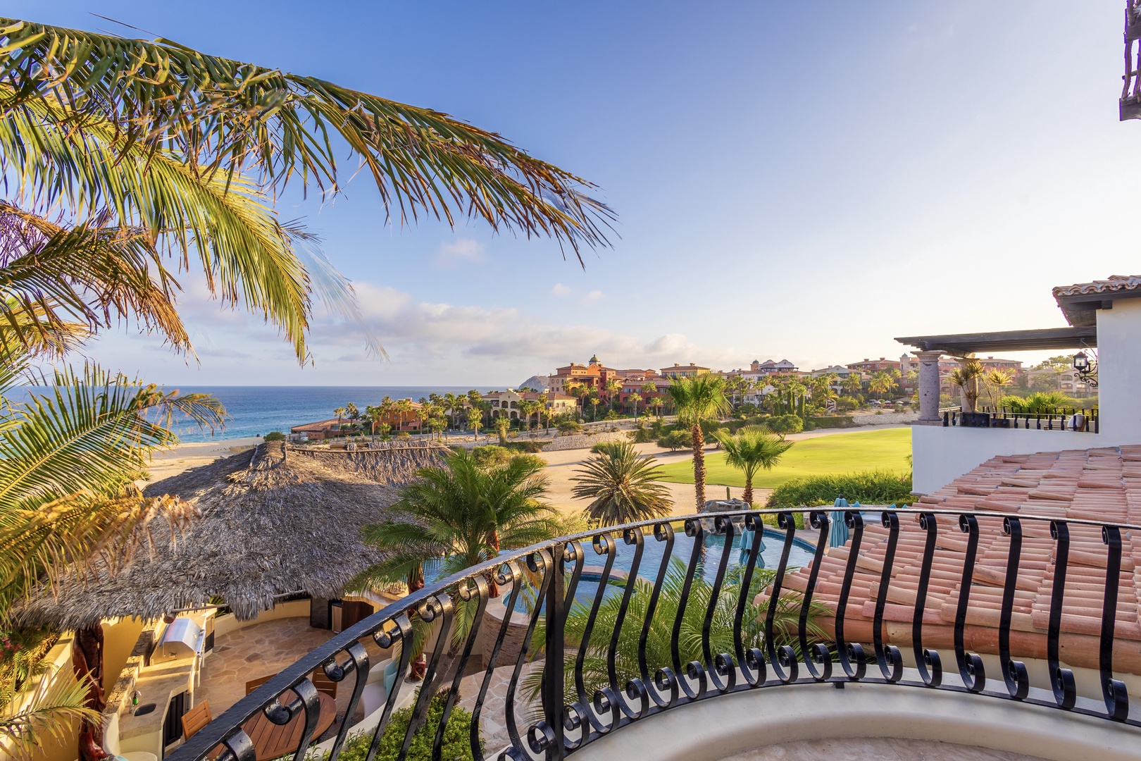 Coastal resort area featuring beachfront access, golf course, and upscale residential community framed by tropical palms and ocean views.