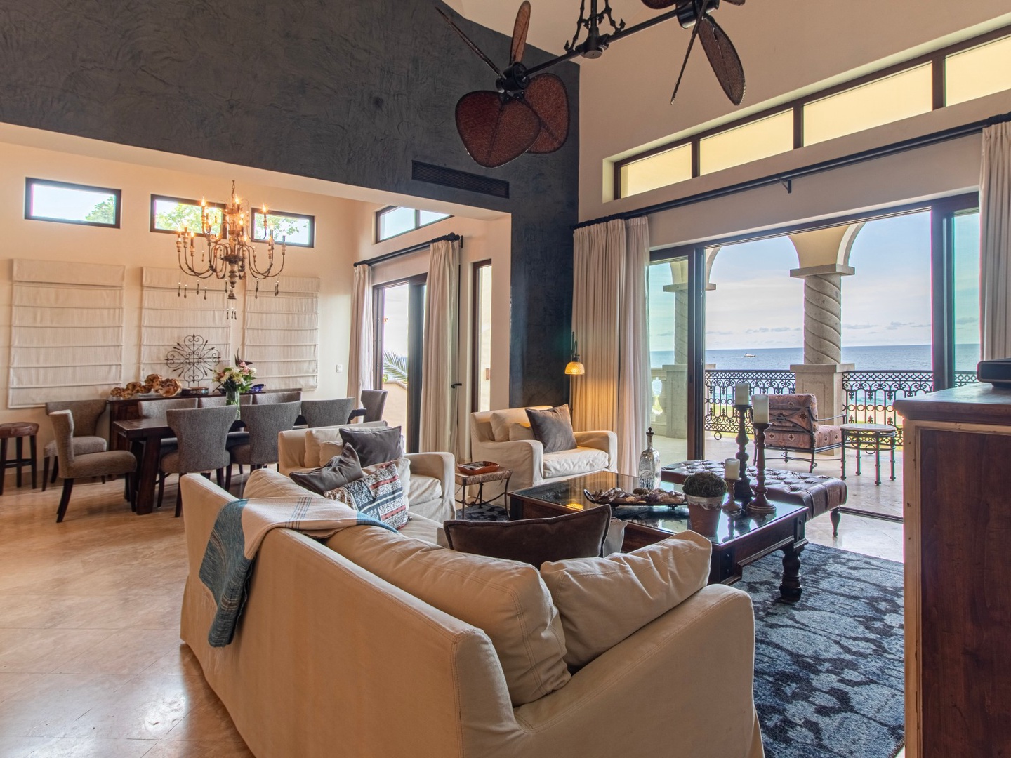 Sink into plush sofas and let the ocean breeze drift through the open balcony doors. Your elegant living space flows into a dining area, all framed by stunning sea views and a soaring vaulted ceiling.