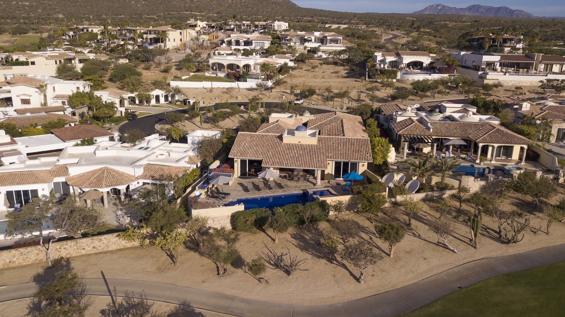 Aerial view of luxury desert vacation rental nestled in an upscale residential community with mountain backdrop and desert landscape.