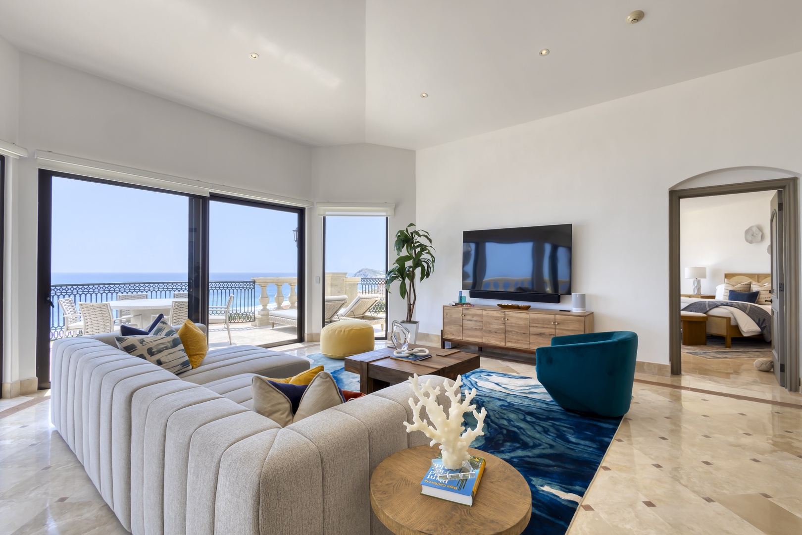 Unwind in your elegant living space, featuring designer furnishings, coastal accents, and stunning sea views framed by expansive glass doors that open to your private terrace.