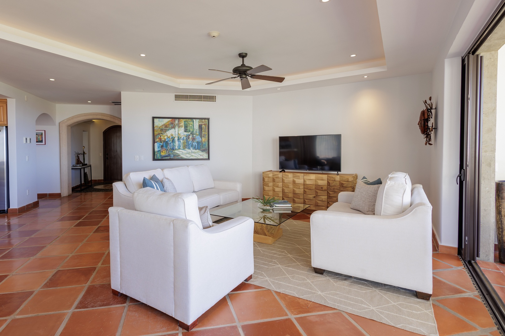 Sink into plush white sofas in your spacious living room, where terracotta floors add warmth, a ceiling fan keeps you cool, and your favorite shows await on the flat-screen.