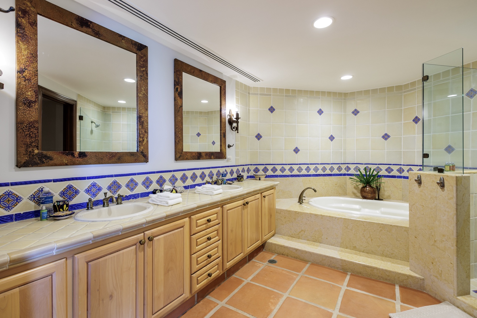 Unwind in your private spa-like bathroom featuring a soaking tub, dual vanities with rustic mirrors, and vibrant hand-painted tile accents—your perfect retreat after a day of adventure.