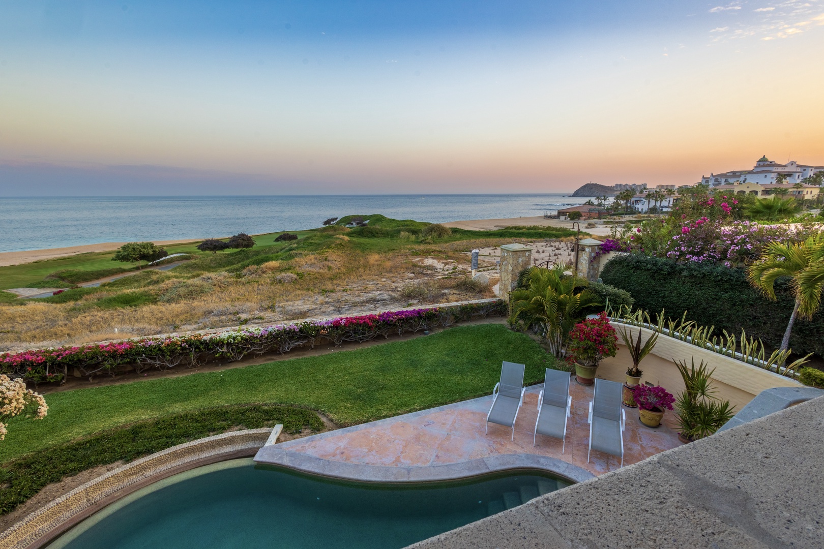 Beachfront property featuring ocean views, lush tropical gardens, and a private pool overlooking the Sea of Cortez at sunset.