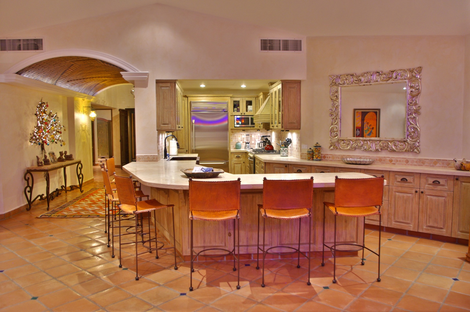 Gather around the spacious island in your fully-equipped kitchen, where warm terracotta tiles and elegant archways create an inviting space for cooking and conversation together.
