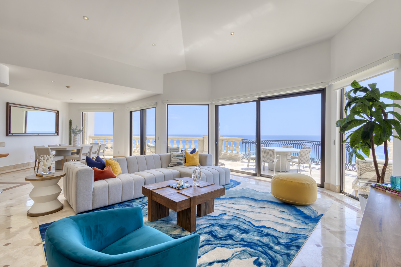 Sink into plush seating and let the vibrant ocean blues wash over you. Sunlight streams through floor-to-ceiling windows, framing endless sea views from your expansive living room—your personal retreat.