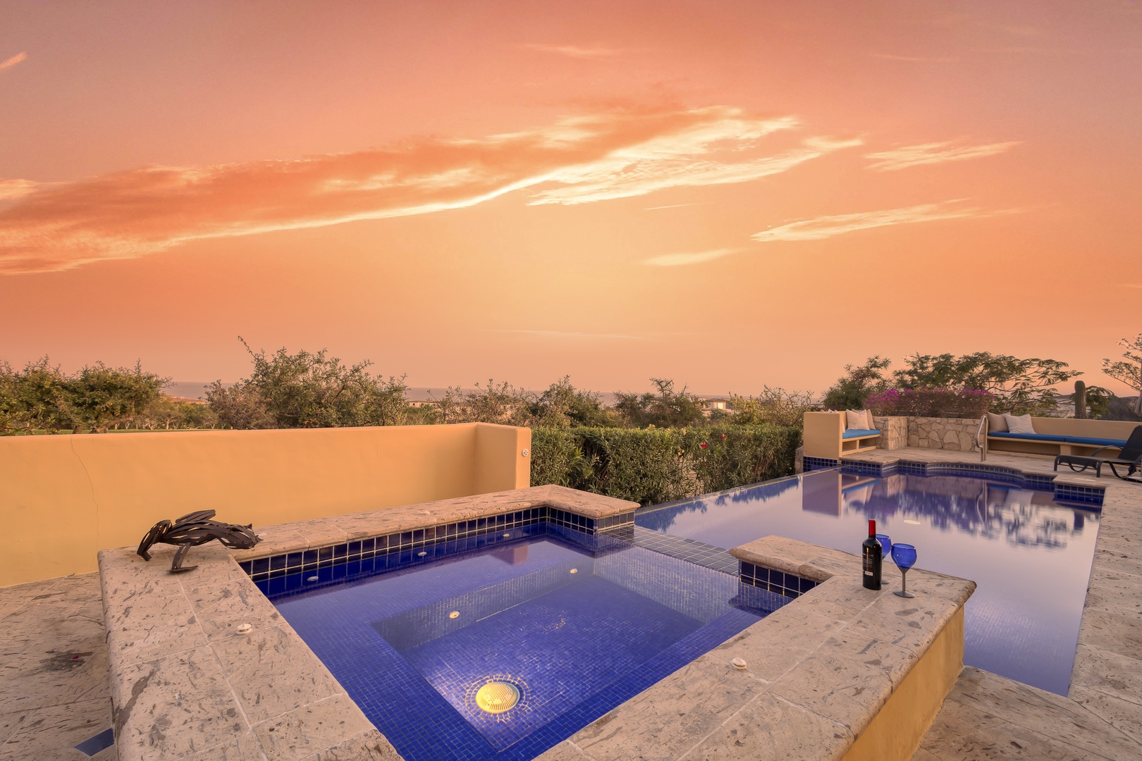 Stunning sunset views paint the sky in warm hues over this peaceful pool terrace, surrounded by lush tropical vegetation.
