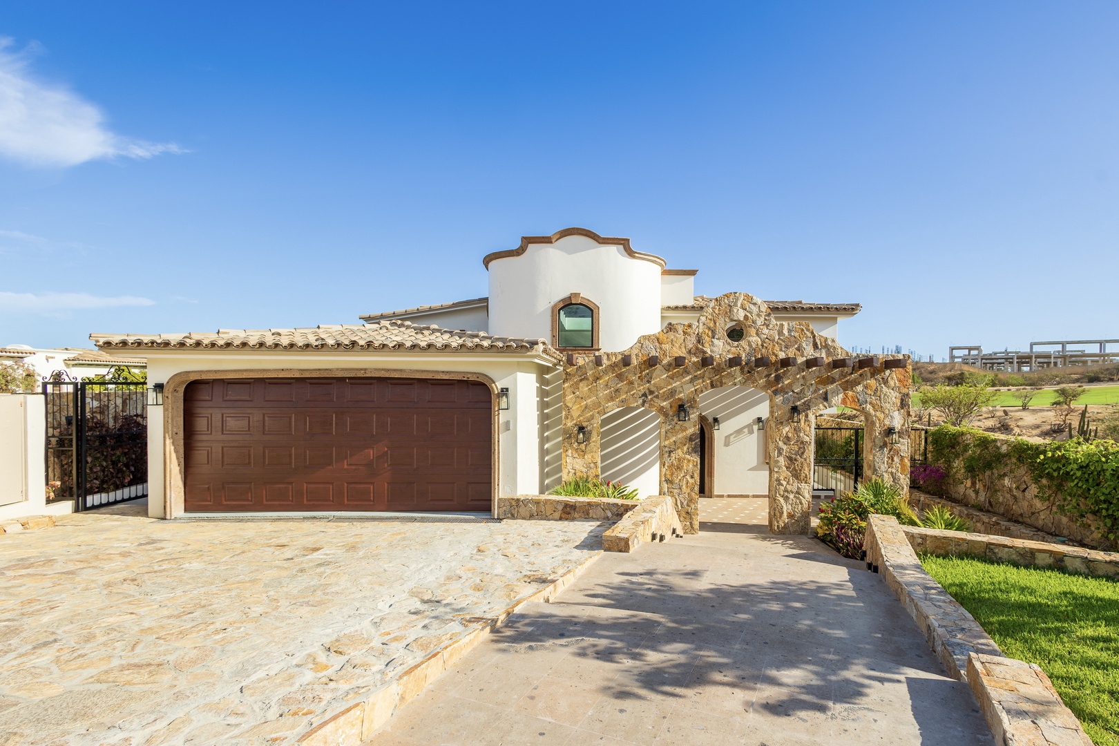 Spanish colonial-style villa set along a golf course with stone accents, arched entry, and mountain backdrop, offering a peaceful desert retreat.