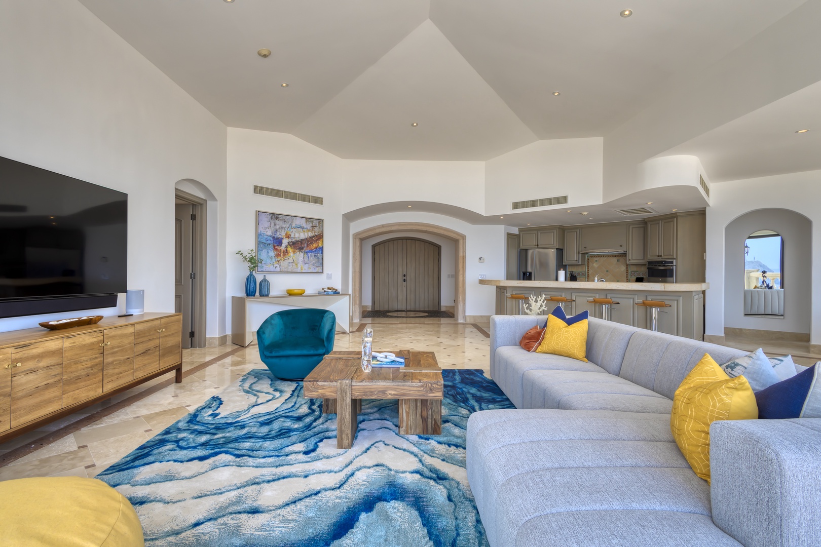 Picture yourself unwinding in this bright open-concept space where coastal hues meet airy arches. The plush sectional and elegant kitchen invite you to relax and entertain effortlessly.