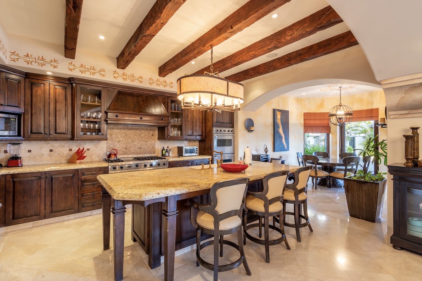 Gather around the grand island in this gourmet kitchen, where rustic beamed ceilings meet chef-grade appliances. Sunlight streams through arched doorways, inviting you to cook, laugh, and create unforgettable vacation memories together.