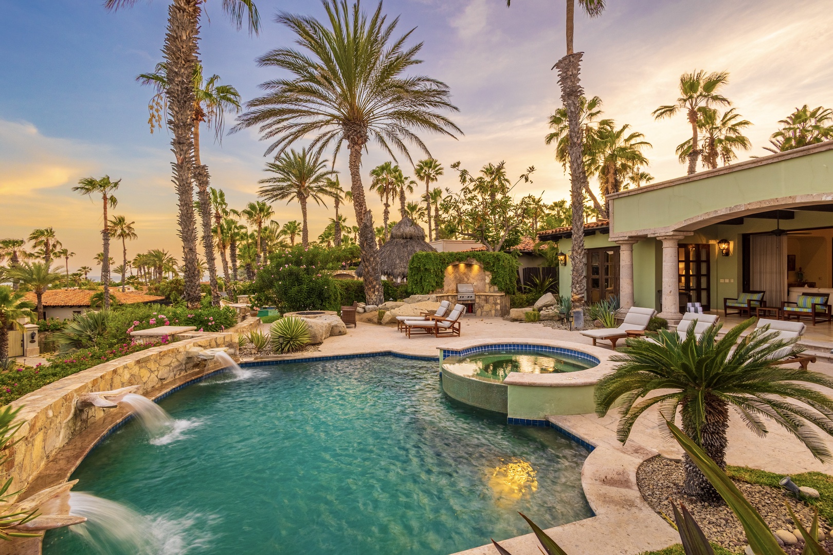 A tropical paradise awaits in the surrounding area, where lush palms frame this elegant desert resort setting at twilight.