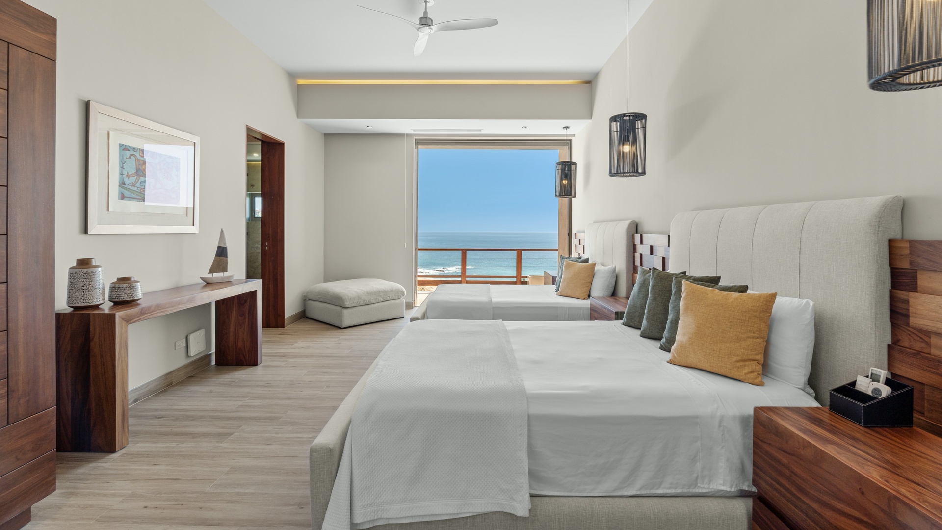 Relax in your serene coastal retreat with plush bedding, warm wood accents, and a stunning ocean view framed by your private balcony—your perfect escape awaits.