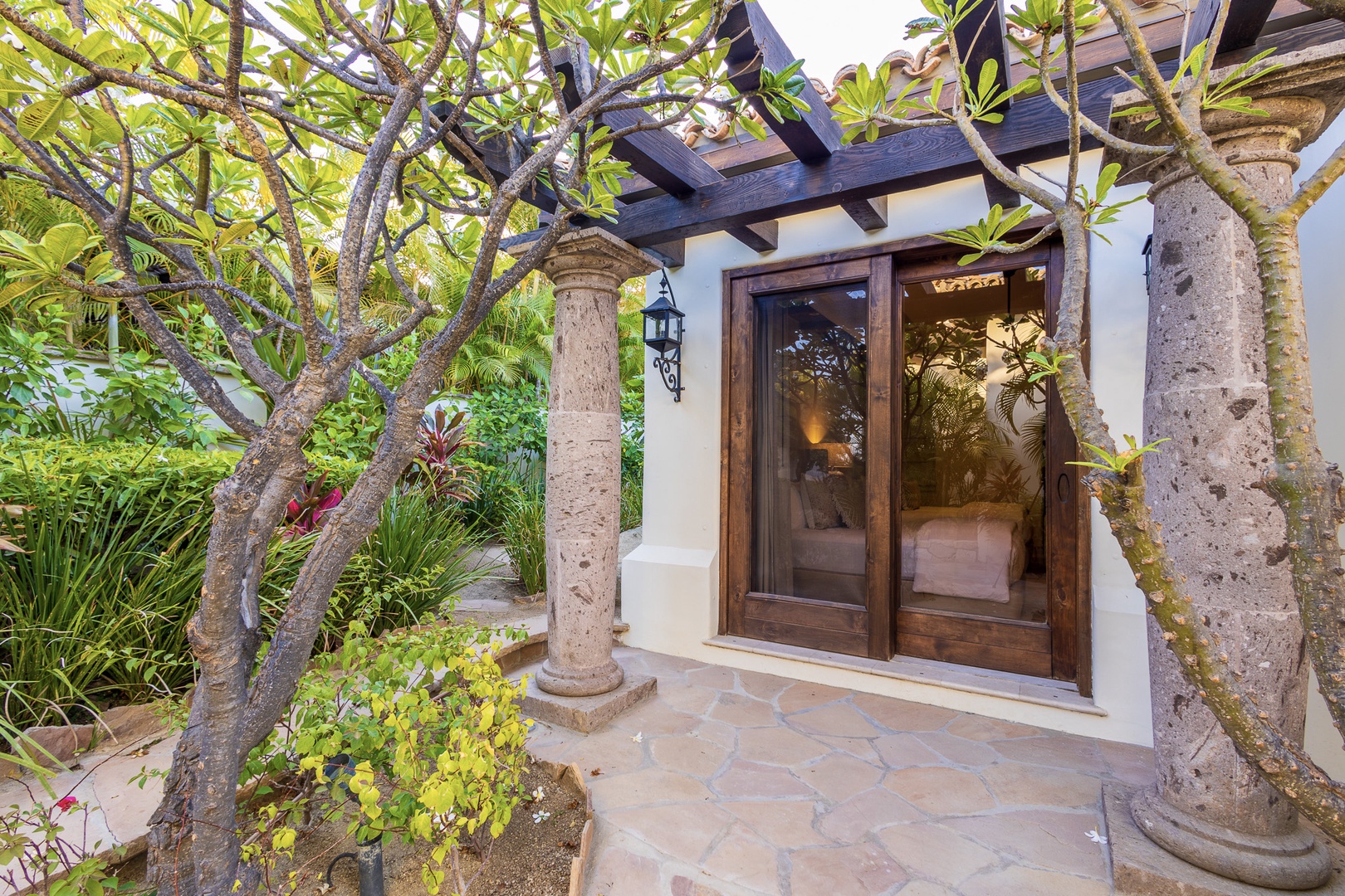 A peaceful entrance framed by tropical foliage and natural stone columns, welcoming you into your private retreat surrounded by lush gardens.
