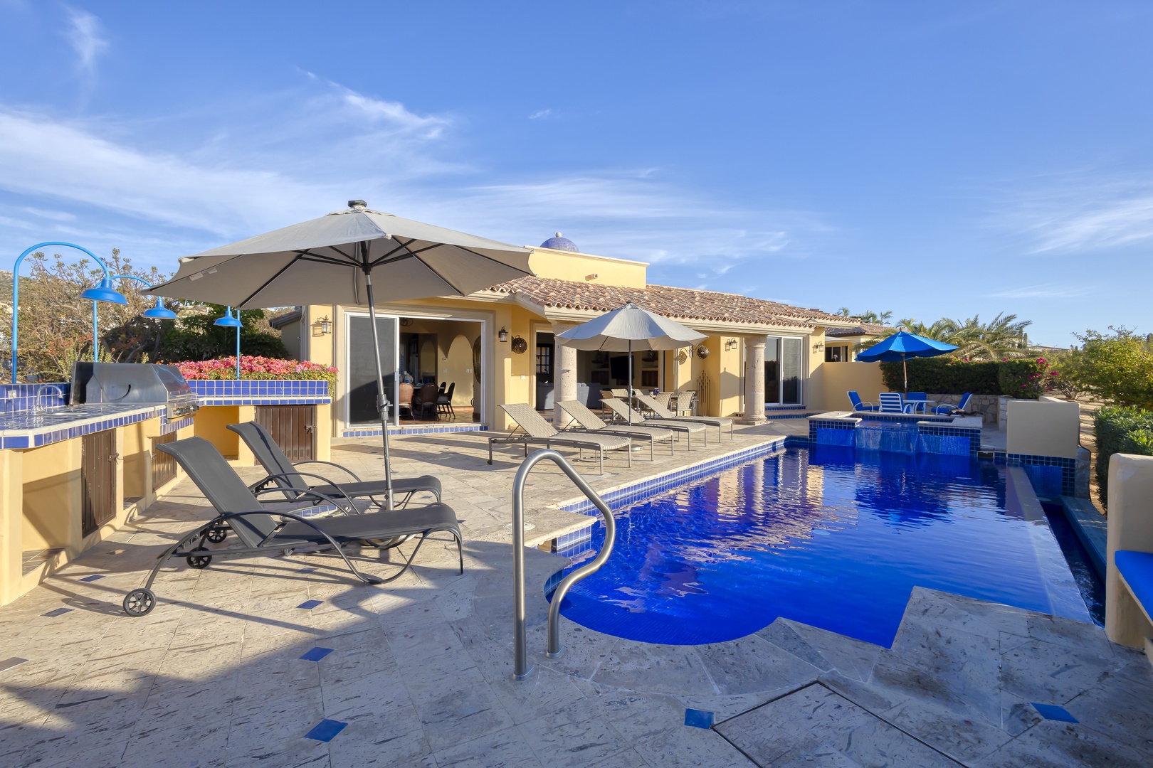 Your private oasis awaits with a stunning blue-tiled pool, comfortable loungers, and shaded seating areas perfect for relaxing under the warm sun.
