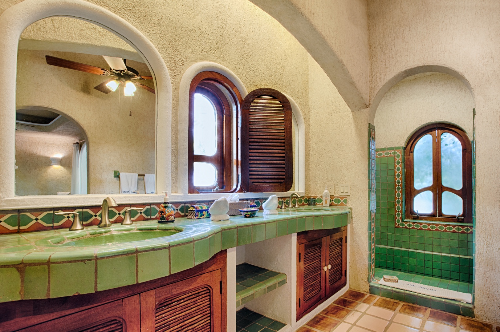 Step into your stunning bathroom featuring vibrant green tiles, arched doorways, and rich wood accents that create a luxurious Mexican-inspired retreat.