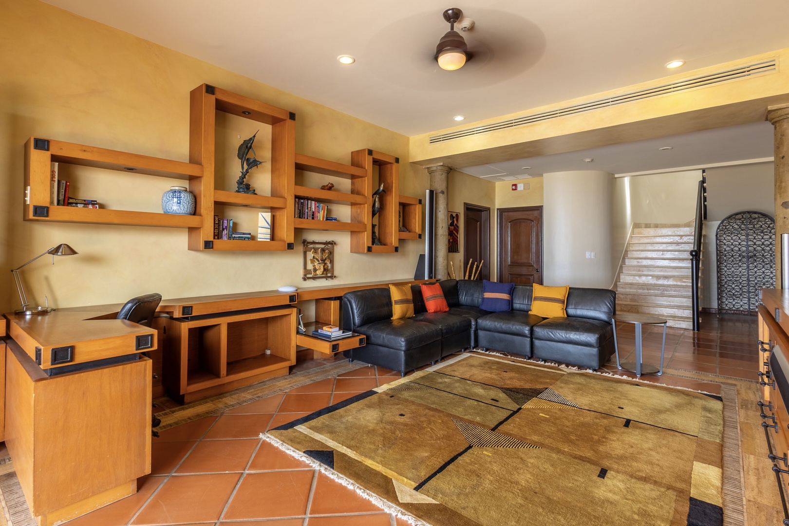 Unwind in your spacious living area, where warm tones and custom wood shelving create a cozy yet stylish retreat perfect for relaxing or catching up on work.