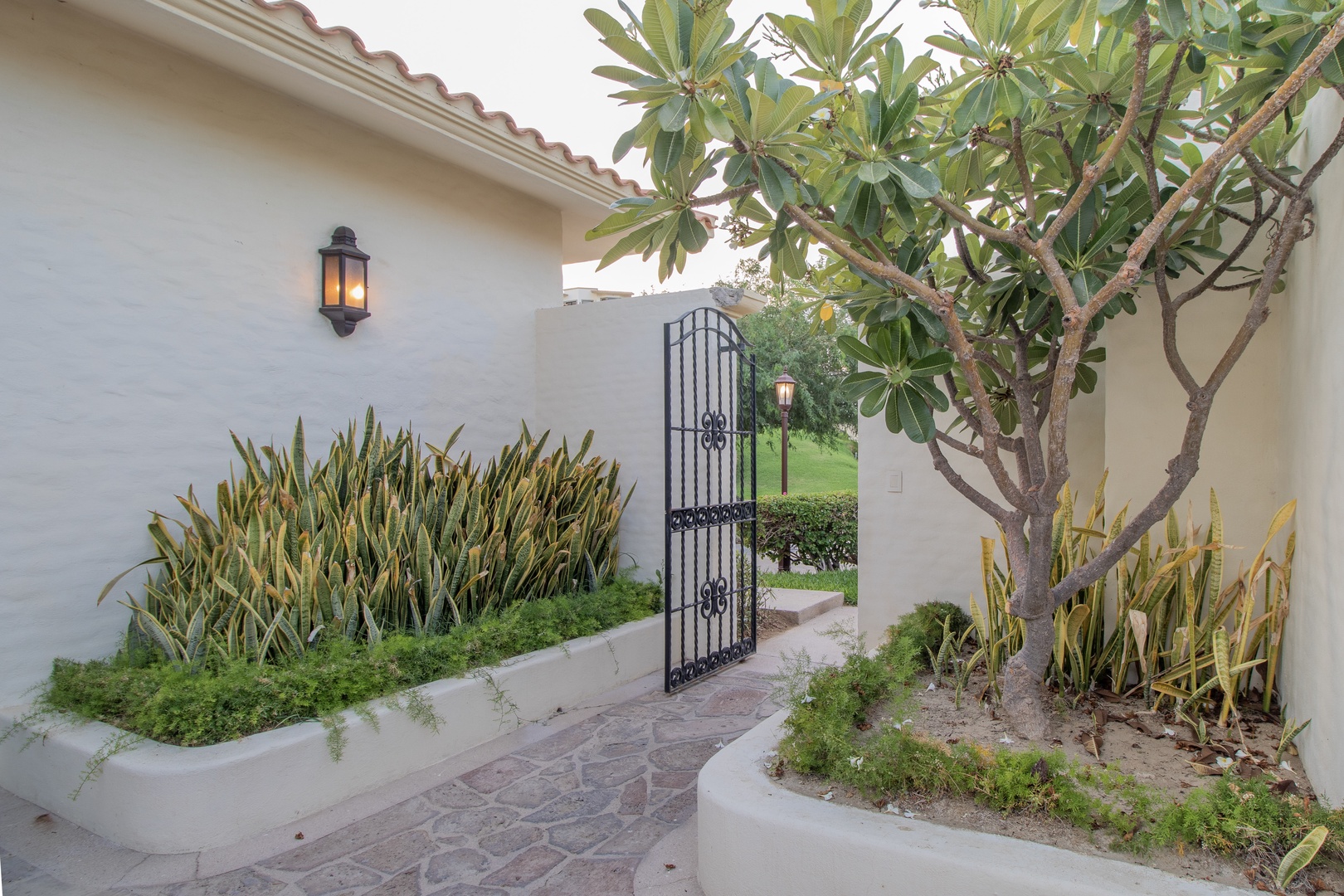 A private courtyard entry with decorative ironwork gate and lush landscaping marks the path to this inviting retreat.