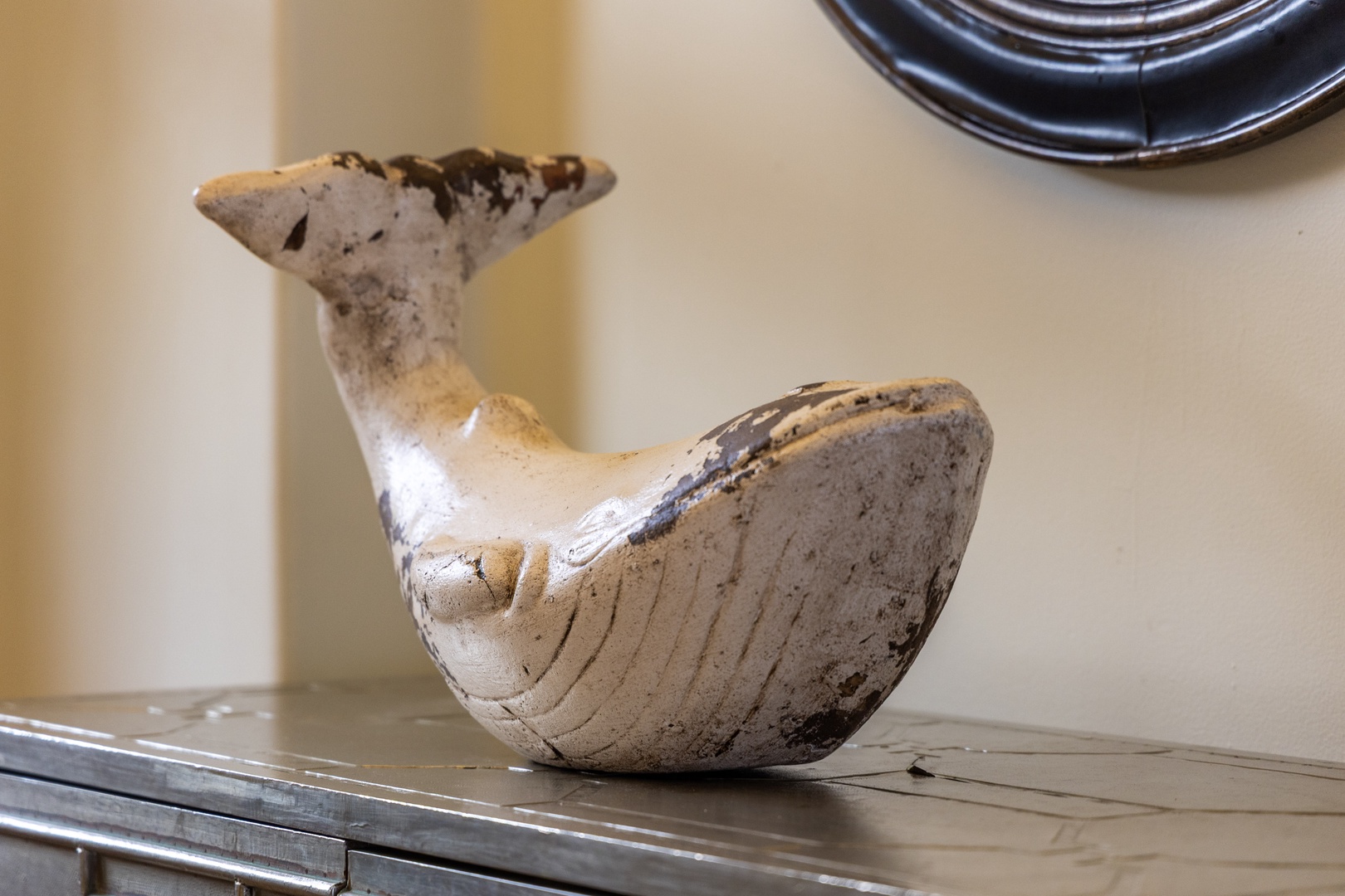 A charming weathered whale sculpture adds coastal character and personality to your space.