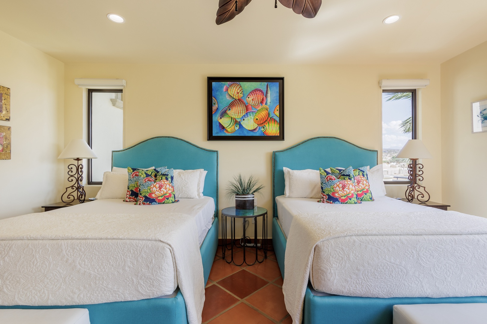 Unwind in your bright coastal bedroom with two plush beds dressed in crisp linens and vibrant tropical accents, perfectly designed for your relaxing getaway.
