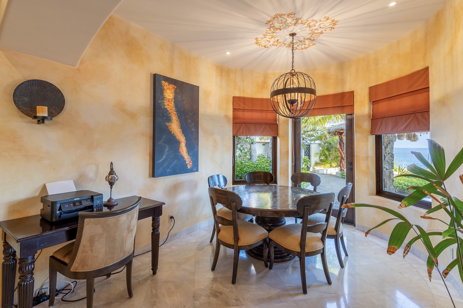 Gather around your private dining table beneath an ornate chandelier, where warm textures and ocean breezes through open windows create the perfect setting for memorable meals together.