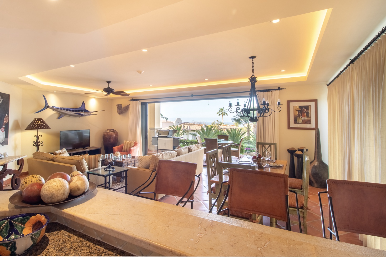 Step into your spacious living and dining area, where elegant decor meets ocean views. Relax under ambient lighting, enjoy meals together, and unwind in style with tropical breezes just beyond your doors.