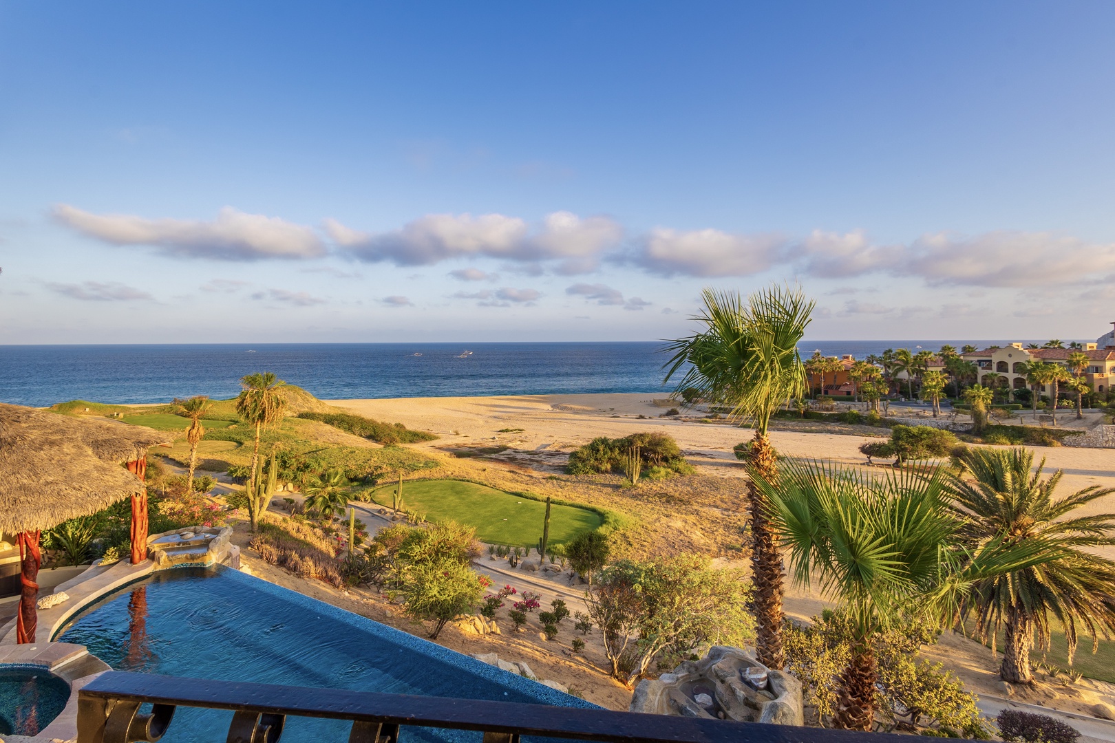Stunning beachfront location with panoramic ocean views, lush tropical landscaping with palms, and a sparkling private pool overlooking golden sands and azure waters.