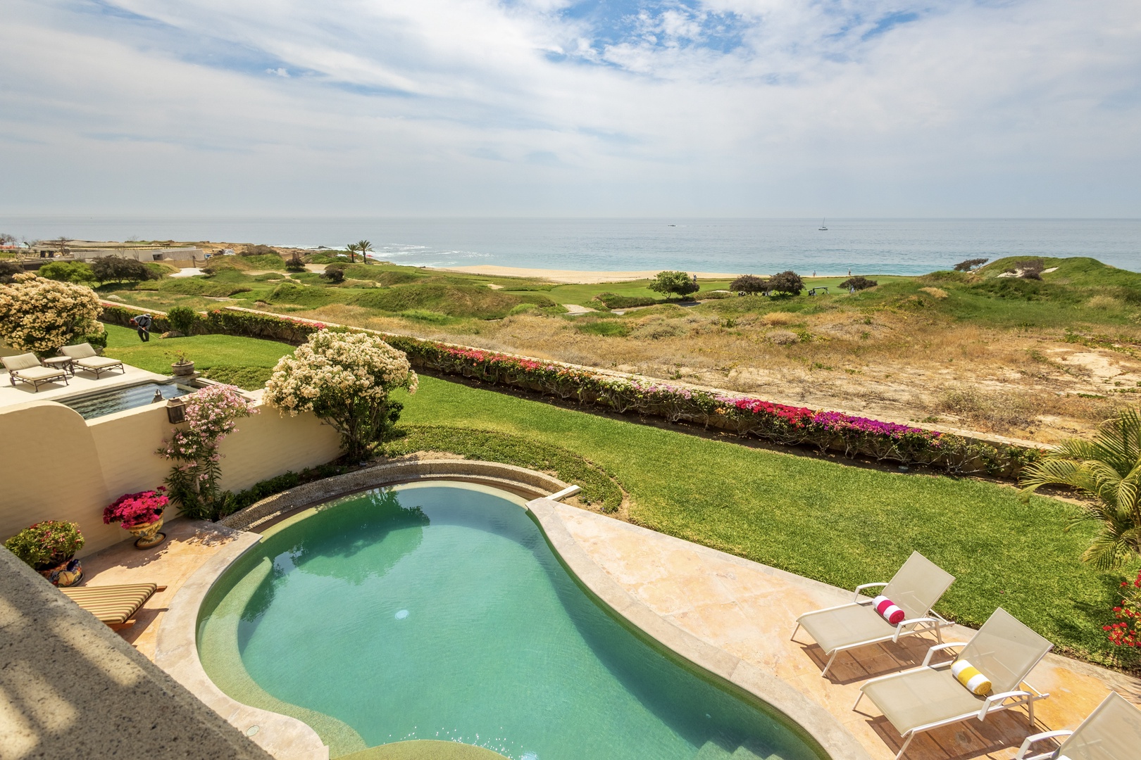 Oceanfront paradise features a private pool framed by lush gardens, manicured lawns, and direct beach access overlooking pristine shores.