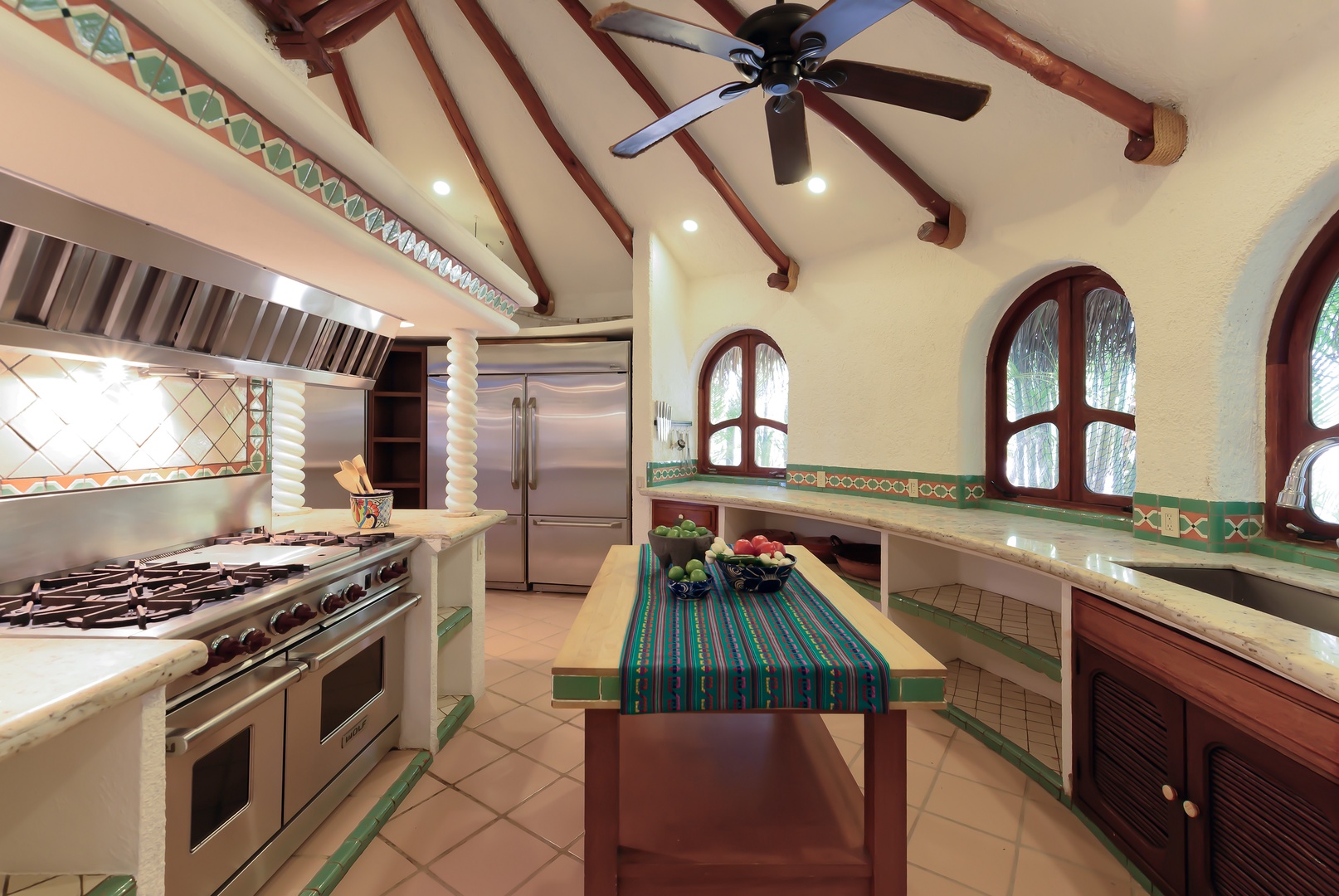 This beautifully appointed kitchen invites you to prepare memorable meals with its spacious layout, professional-grade range, and charming arched windows that frame tropical views and fill the space with natural light.