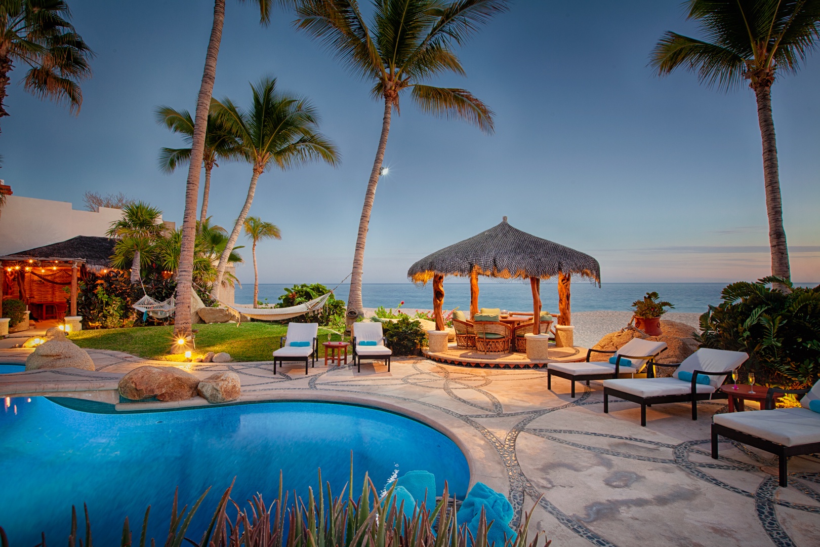 Tropical paradise with palm-fringed pool and private beachfront gazebo creating the perfect oceanside retreat setting.