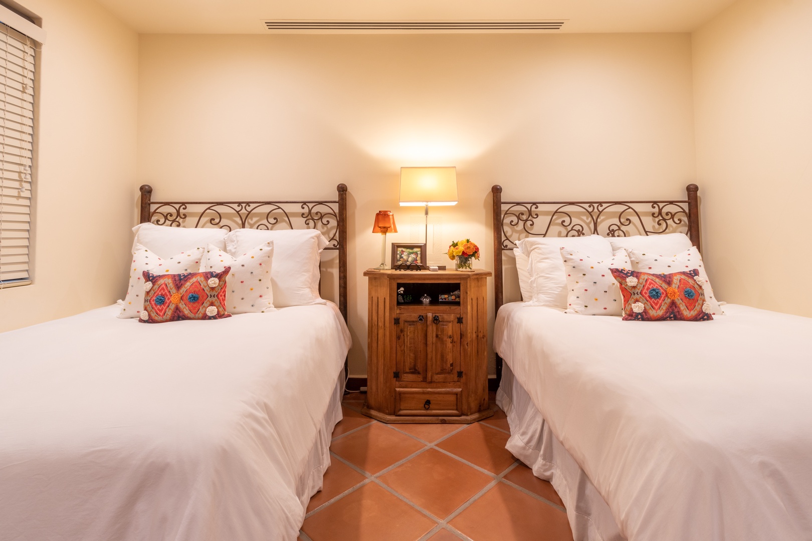 Drift off to peaceful sleep in this charming bedroom with elegant wrought iron beds, cozy linens, and warm lighting that creates your perfect retreat after a day of adventure.