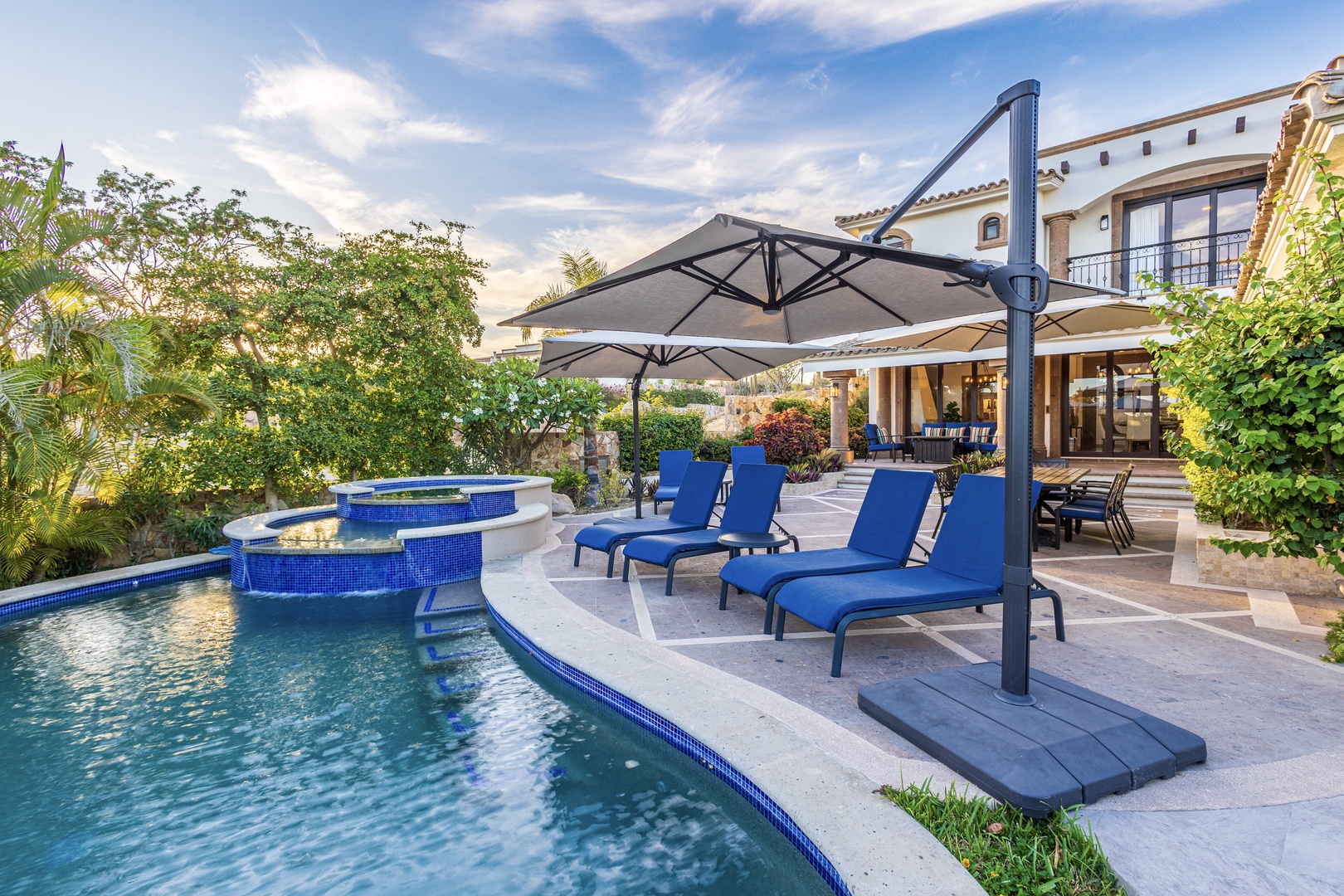 Sink into a plush lounge chair by your private pool, shaded by an elegant umbrella. The jacuzzi beckons, lush gardens surround you, and the open-air patio invites leisurely afternoons under the sun.