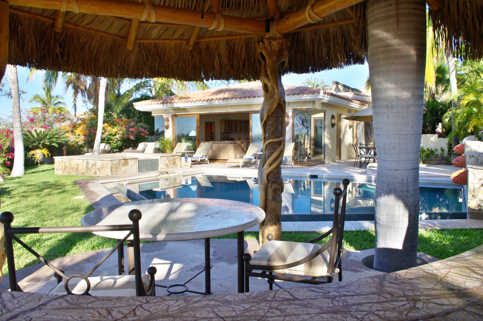 Private villa retreat with shaded palapa dining, sparkling pool, lush tropical gardens, and direct patio access from your suite.
