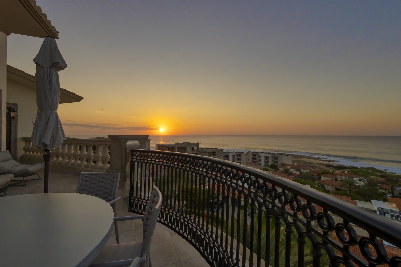 The property offers stunning coastal views with the ocean meeting the horizon at sunrise, positioned above a residential area.