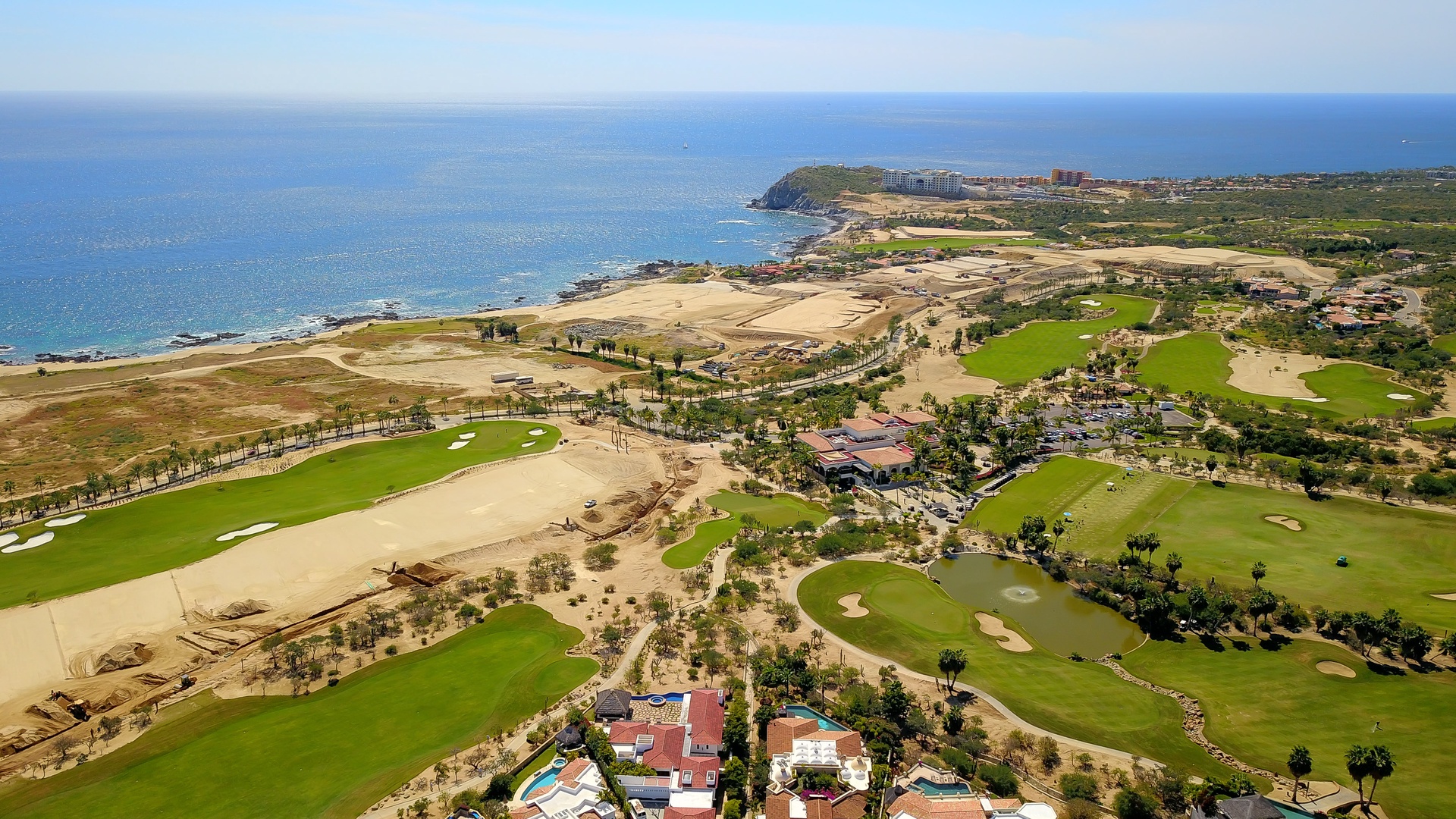Stunning aerial view showcasing the championship golf course nestled along pristine coastline, with multiple fairways and greens creating a golfer's paradise by the sea.