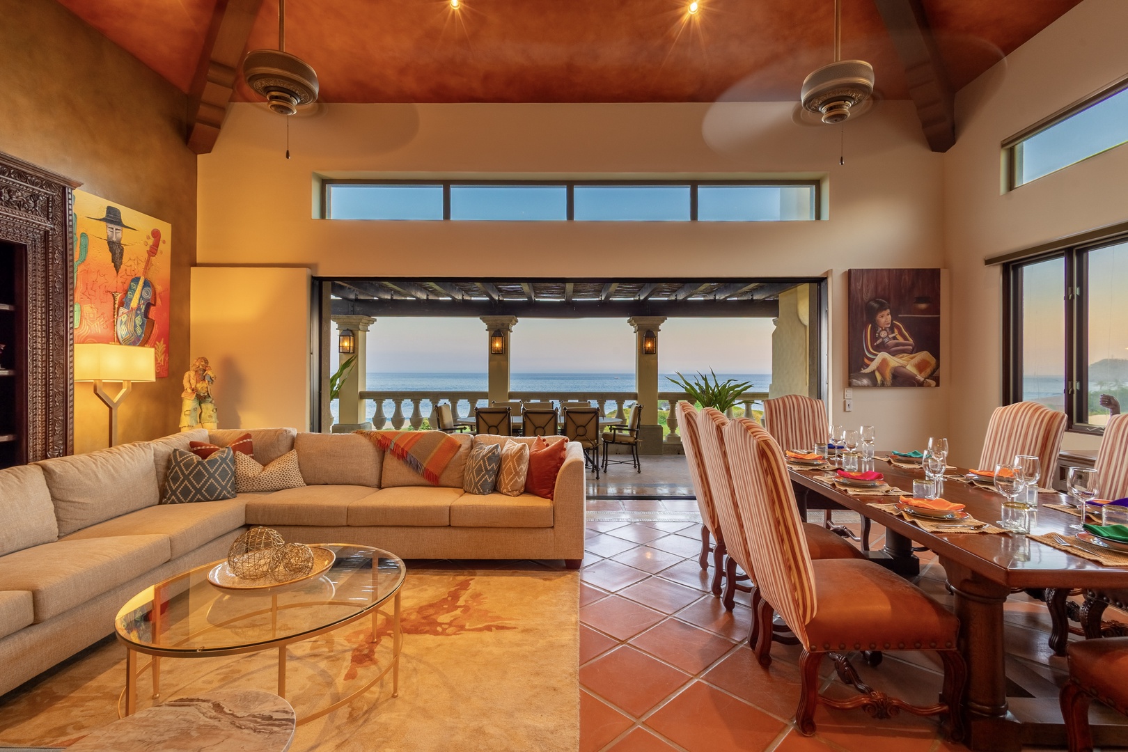 Relax in your spacious living and dining area with stunning views of the ocean. Warm terracotta ceilings, colorful artwork, and cozy furnishings create an inviting space for gathering.