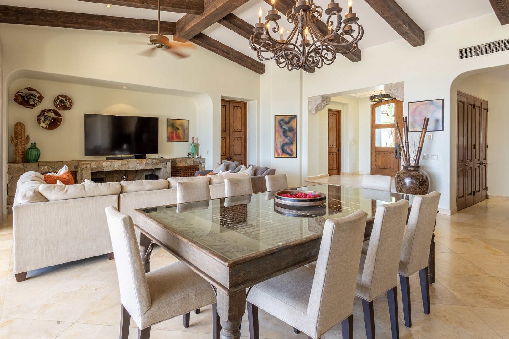 Relax in your elegant open-concept living space with exposed beams, ornate chandelier, and cozy fireplace creating perfect ambiance for gatherings.
