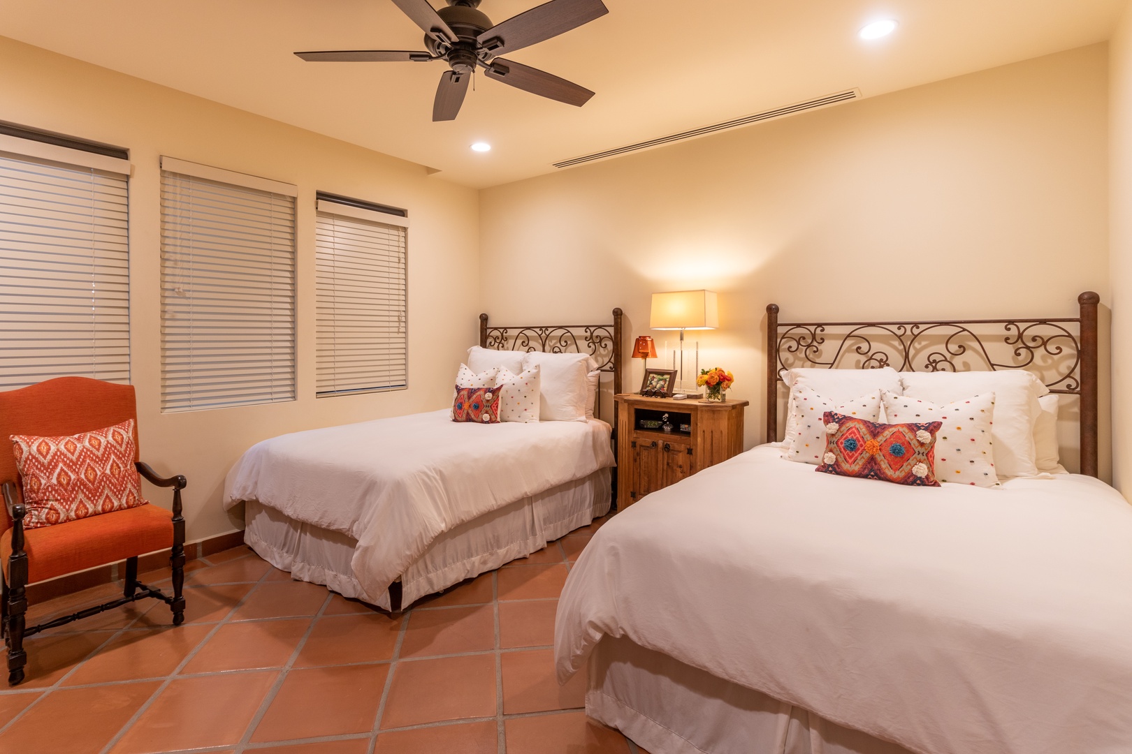 Unwind in your cozy retreat with two plush beds, warm terracotta floors, and soft lighting—perfect for a restful night after exploring all day.