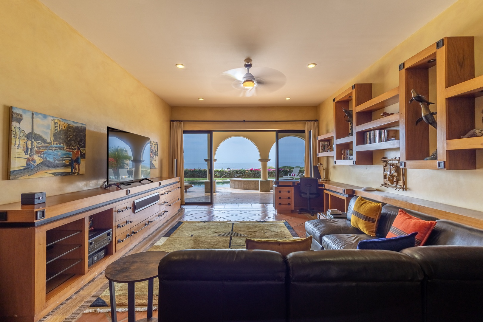 Sink into plush leather seating as you enjoy entertainment with ocean views through stunning arched doors. Custom wood built-ins and warm desert tones create your perfect relaxation retreat.
